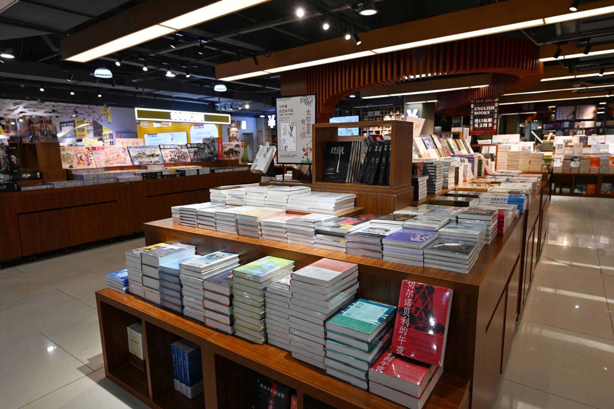 Spacious modern bookstore featuring wooden bookshelves, neatly arranged books, bestseller displays, and a welcoming reading environment.